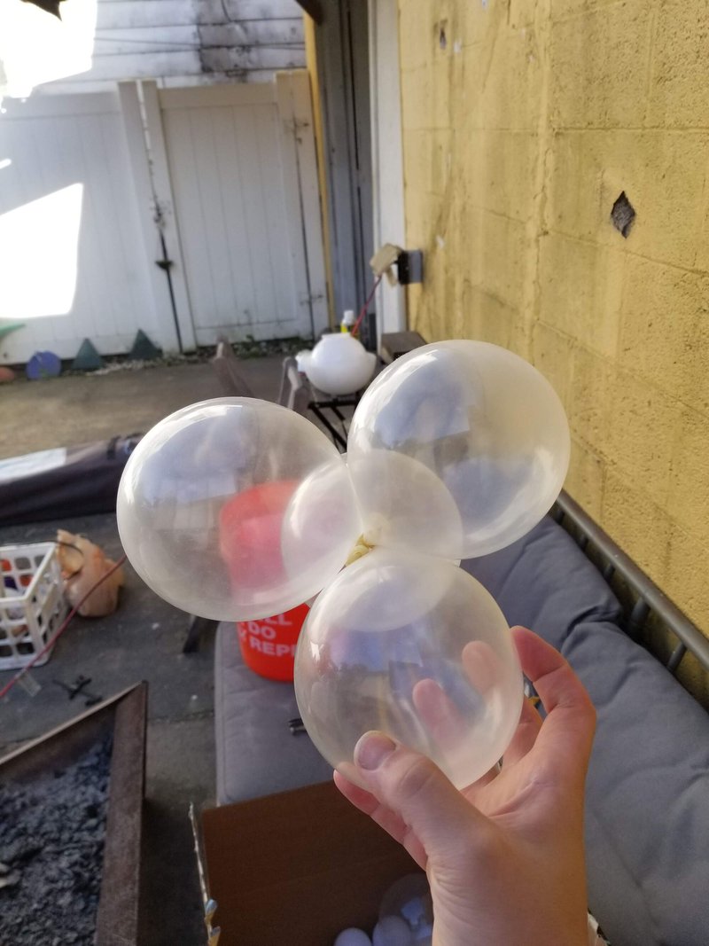 Hand holding translucent inflated plastic spheres in a workshop space with yellow concrete walls
