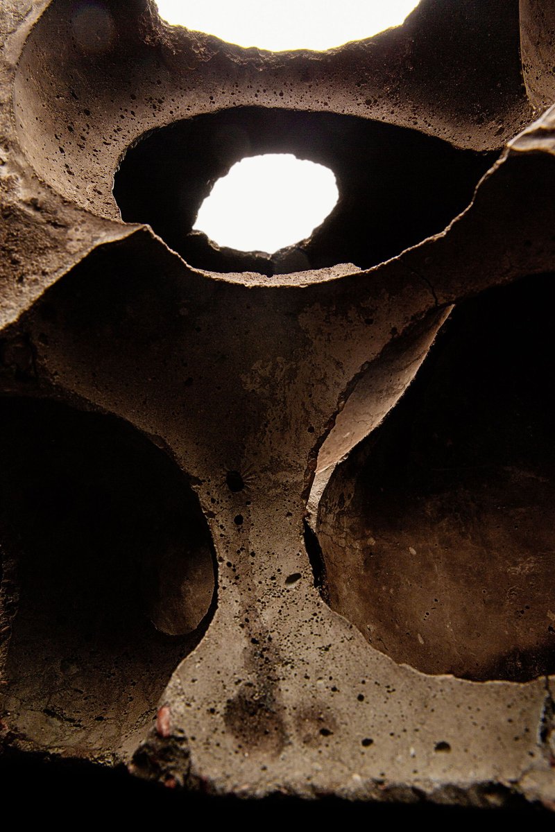 Interior view through overlapping circular voids in a ceramic block with light filtering