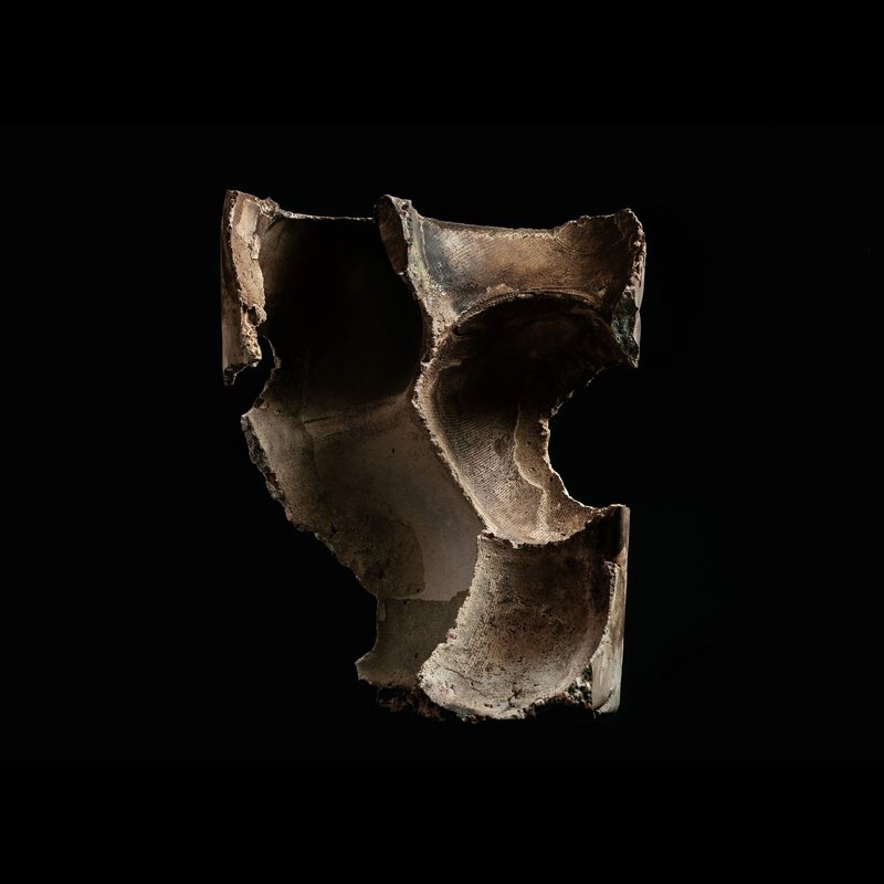 Angled view of a ceramic fragment with curved voids and fractured edges