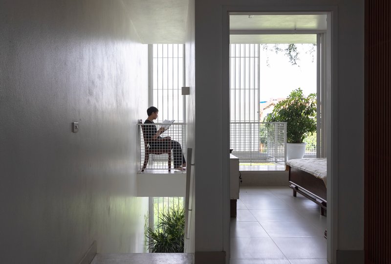 Interior hallway view through doorways to a bedroom with a person seated beside a translucent screen