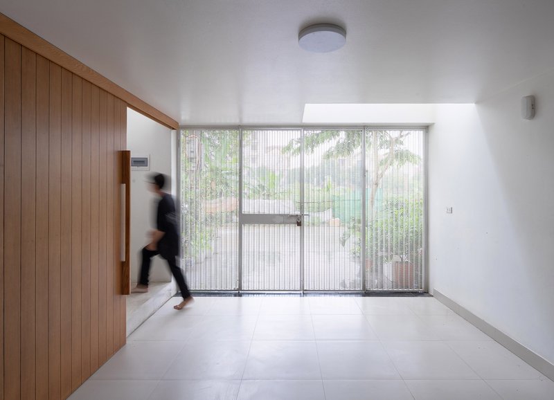 Interior foyer with vertical timber wall and fluted glass entrance doors framing a courtyard with trees