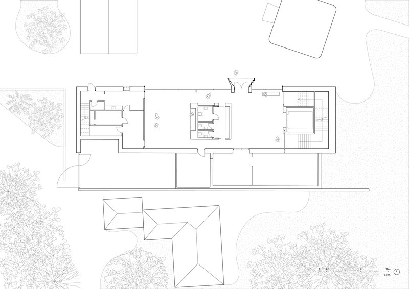 Floor plan drawing showing linear building with interior courtyard and surrounding landscape elements