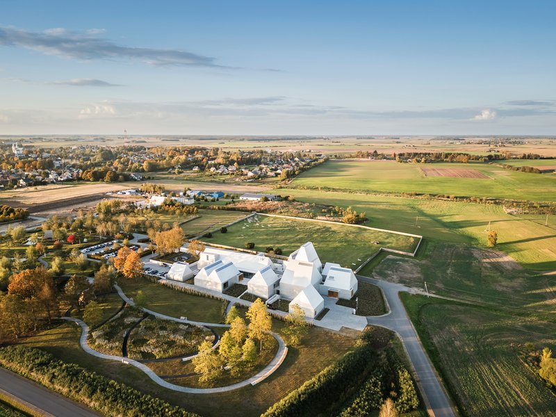 Aerial view of the white multi-lobed roof complex surrounded by agricultural fields and autumn trees