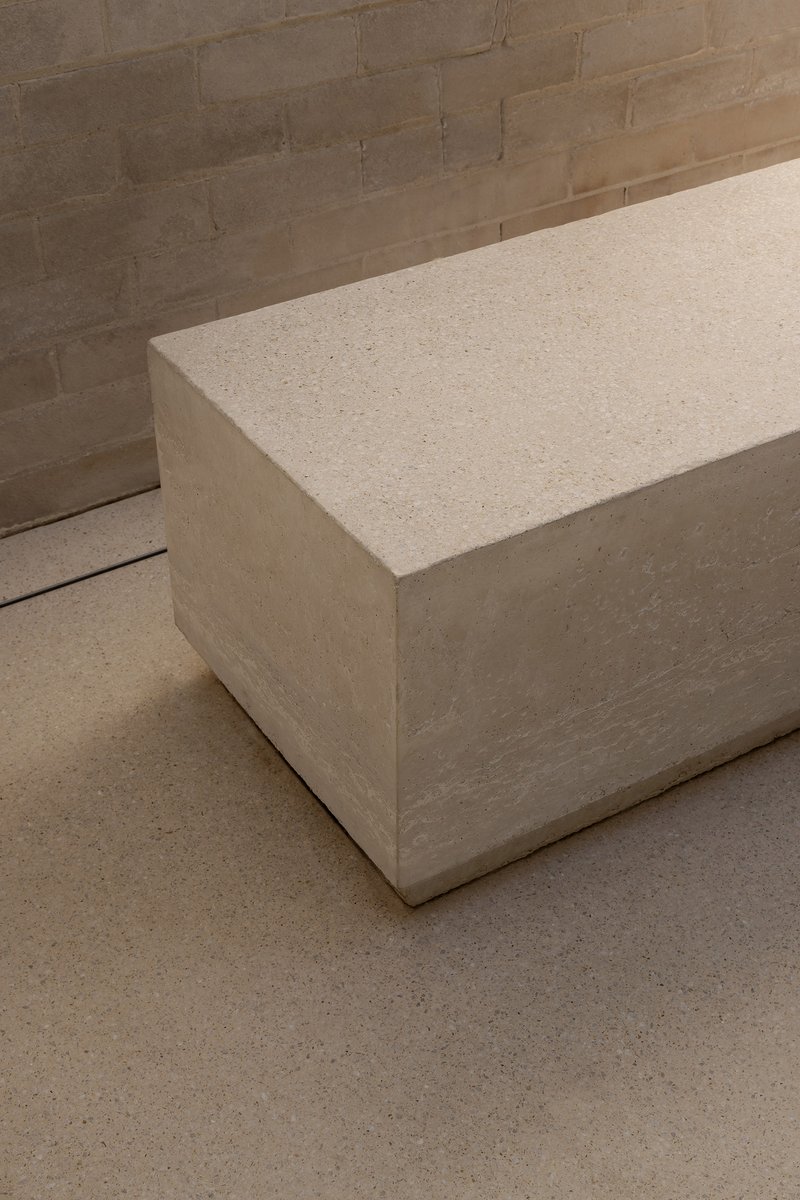 Corner detail of cast stone bench against brick wall with terrazzo floor