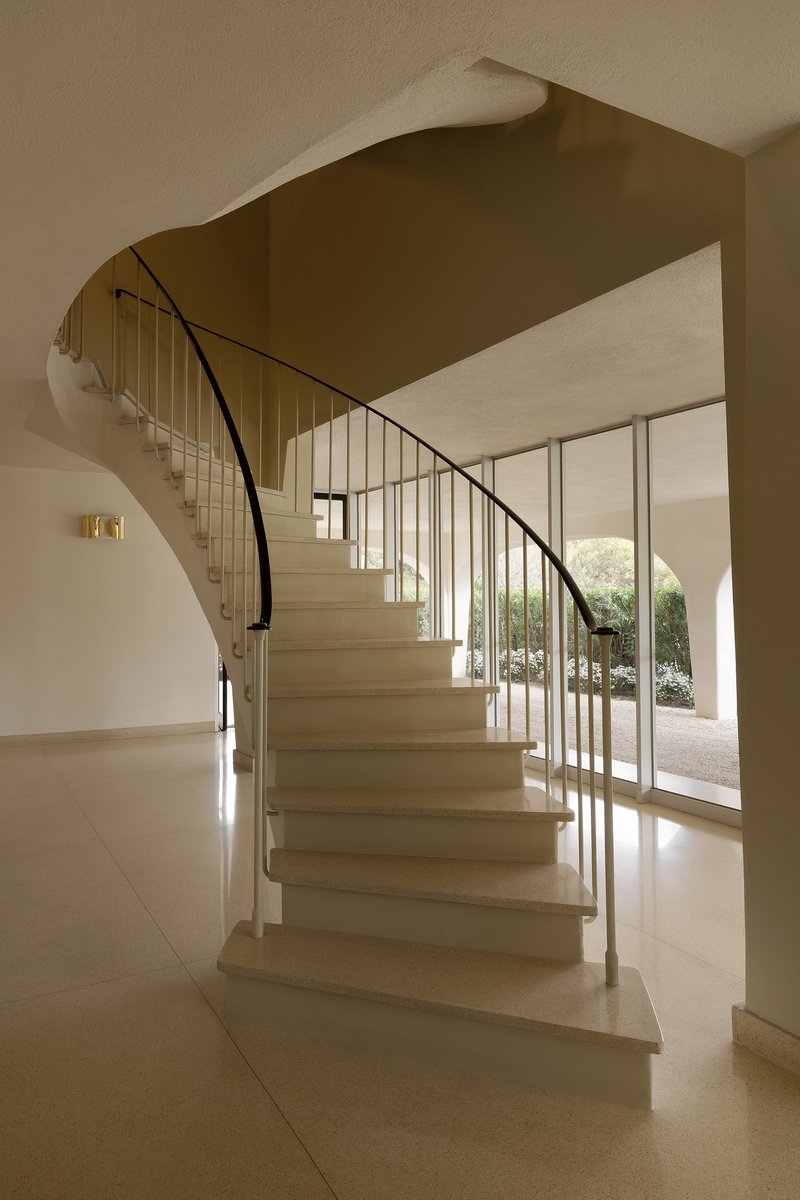 Curved stone staircase with steel rod balustrade and glass doors opening to a courtyard