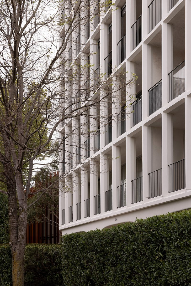 Oblique view of the facade showing concrete columns and balconies with bare tree branches