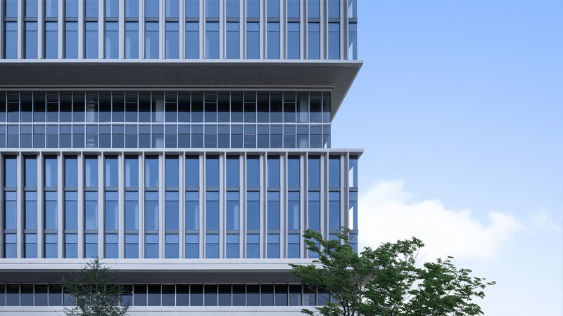Stacked glass facade volumes with horizontal white bands and trees at grade level