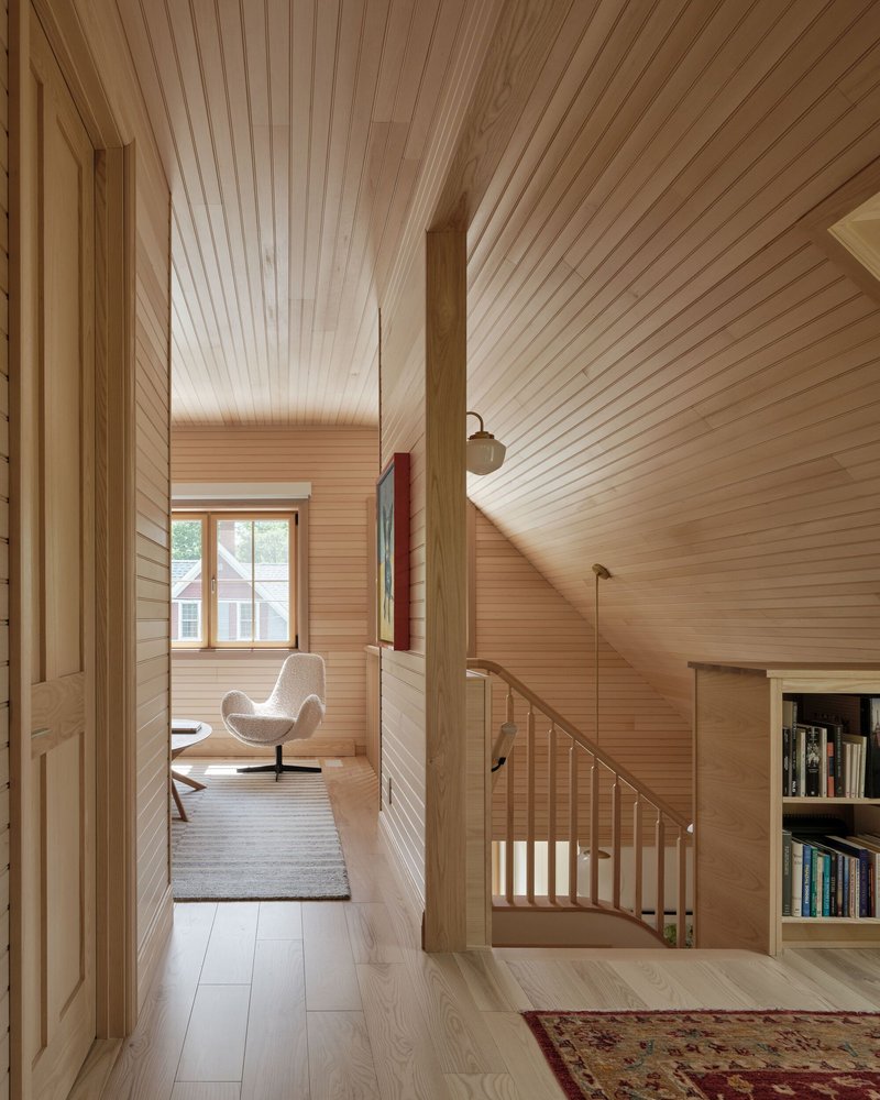 Upper hallway with horizontal wood slat walls and ceiling leading to a windowed sitting nook