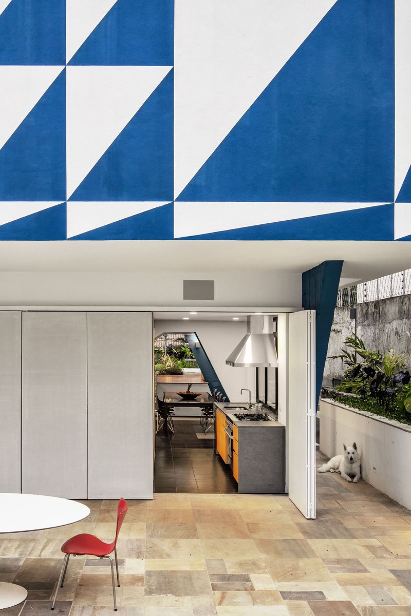 Covered terrace with patterned ceiling overhang looking into kitchen with sliding doors and planted bed