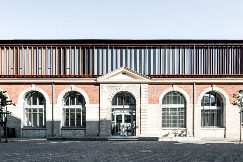 Street facade with arched windows in brick and stone below a vertical slatted timber upper storey