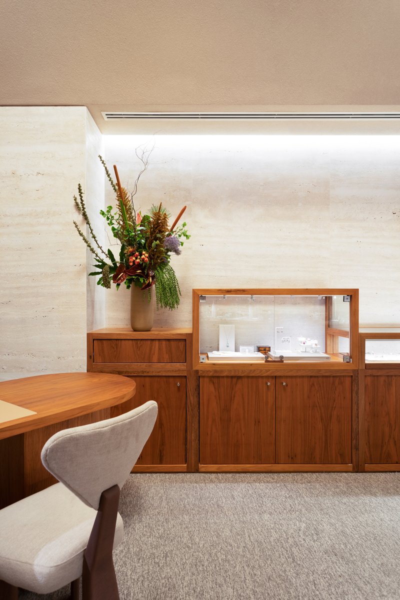 Walnut credenza and glass vitrine below a horizontal window with floral arrangement