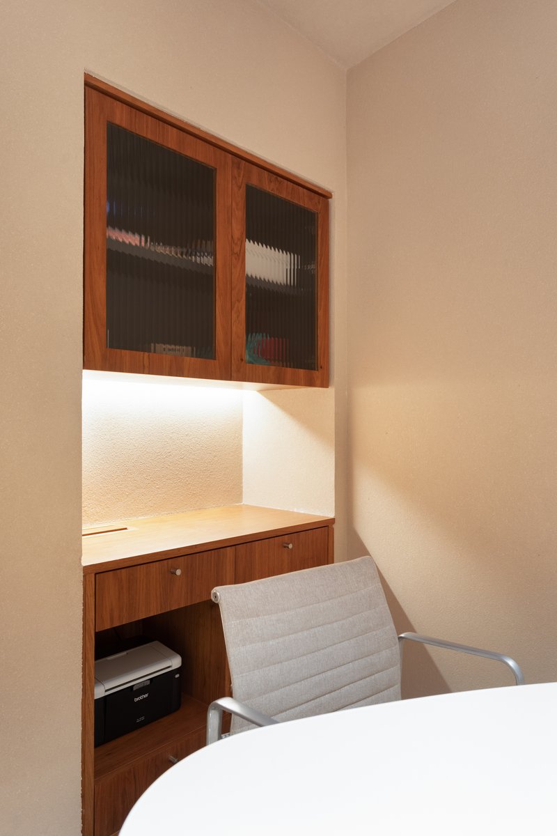 Built-in walnut desk alcove with ribbed glass cabinet doors and integrated LED strip lighting