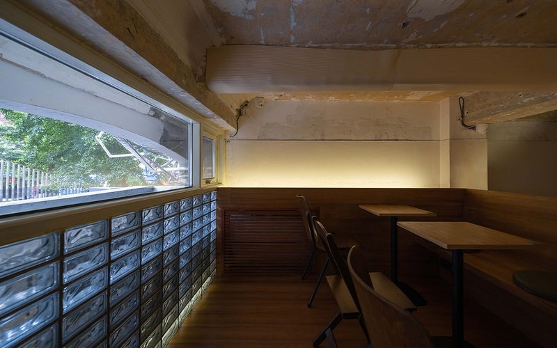 Seating nook with glass block window wall and timber banquette beneath a vaulted ceiling
