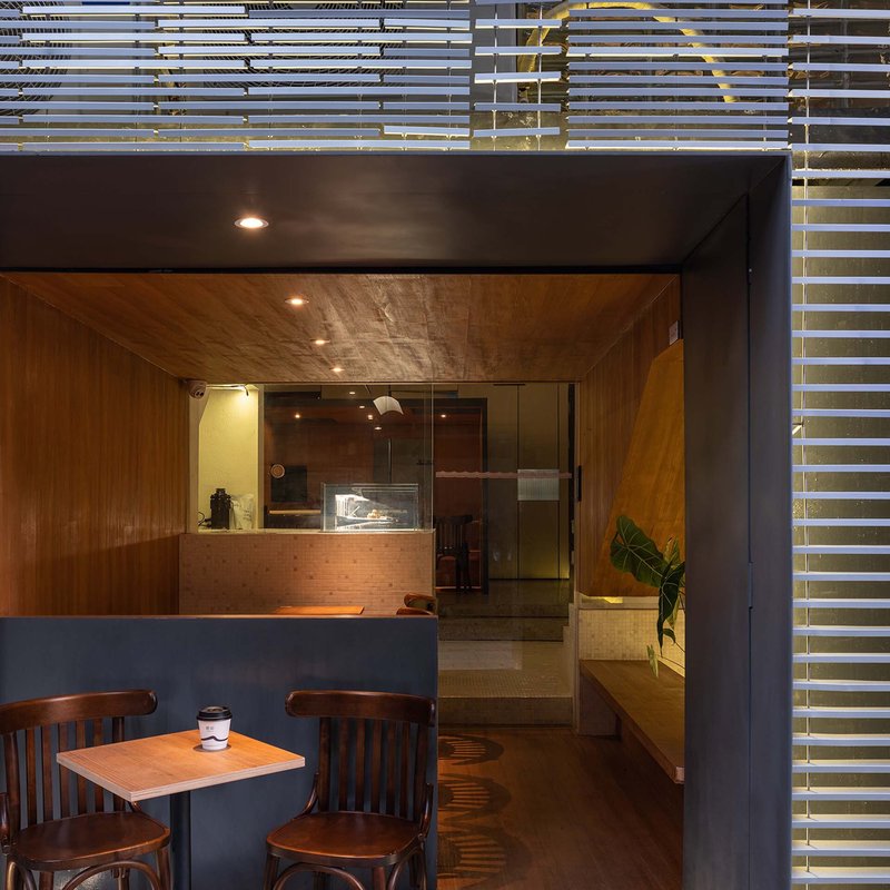 Timber-lined entrance canopy with horizontal slat ceiling above seating area at dusk