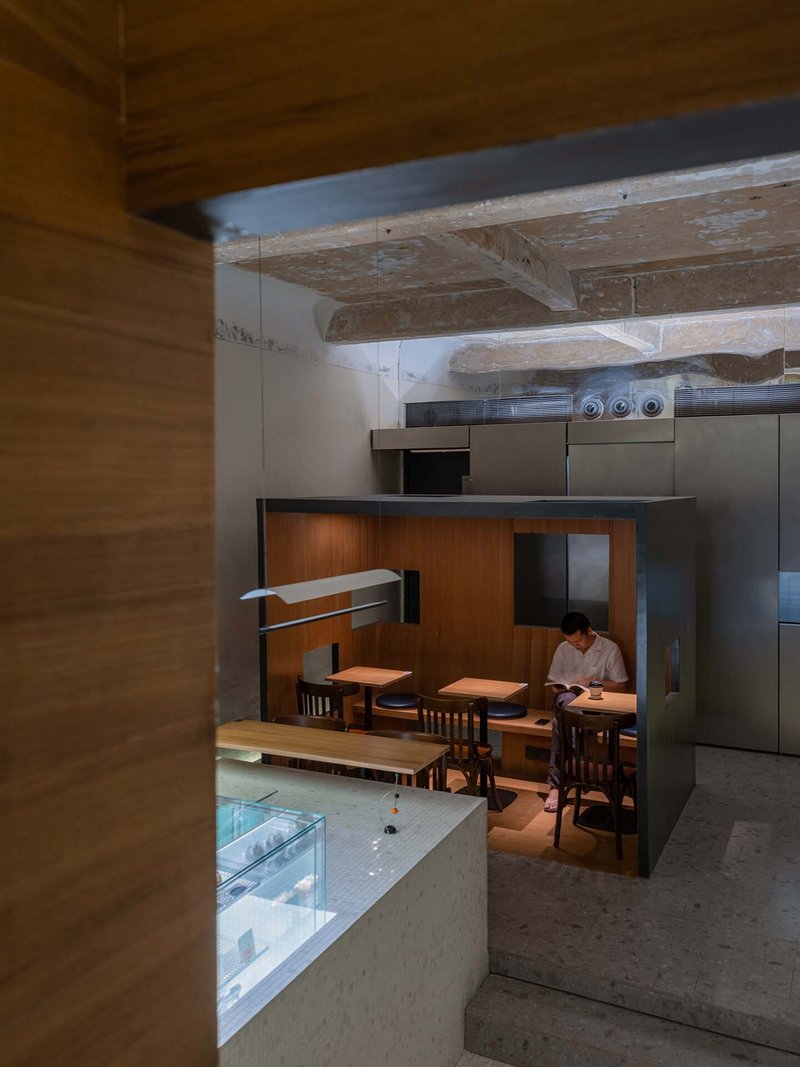 View through timber-clad opening toward dining area beneath exposed timber beams with weathered finish