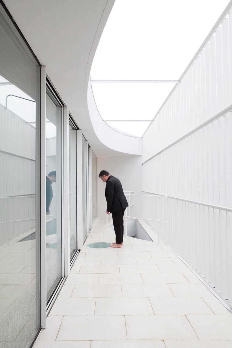 Outdoor terrace with white tile flooring and a person beside a curved skylight opening