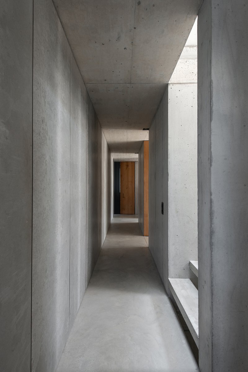 Narrow concrete corridor with clerestory windows casting light onto polished concrete floor