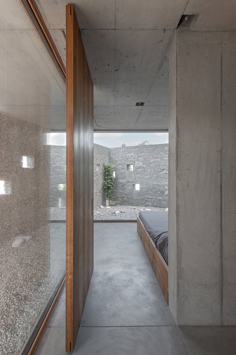 Narrow hallway with timber panel walls and polished concrete floor leading to a pebbled courtyard