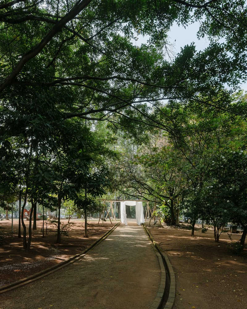 Path through a tree grove leading to a white cubic pavilion in the distance