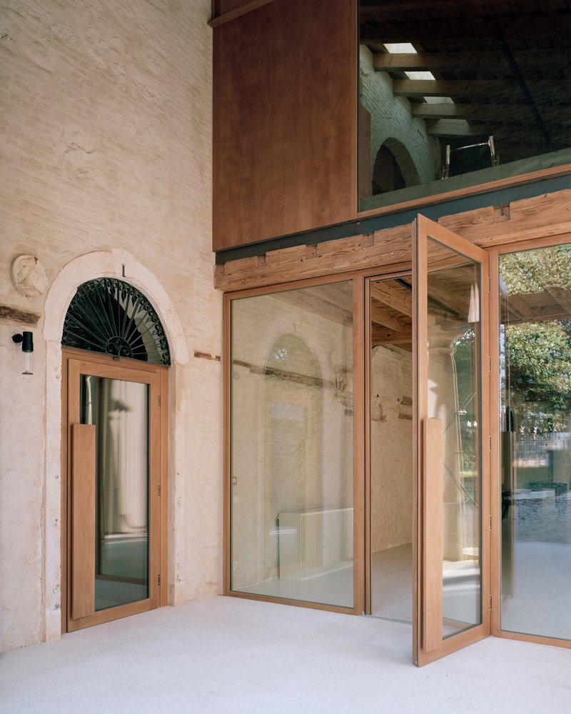 Open timber-framed glass doors with arched transom window and exposed beam mezzanine above