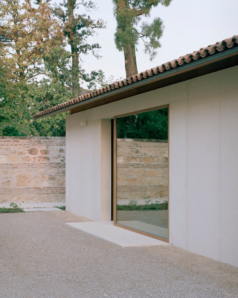 Sliding glass door set into a white rendered wall beneath a clay tile roof