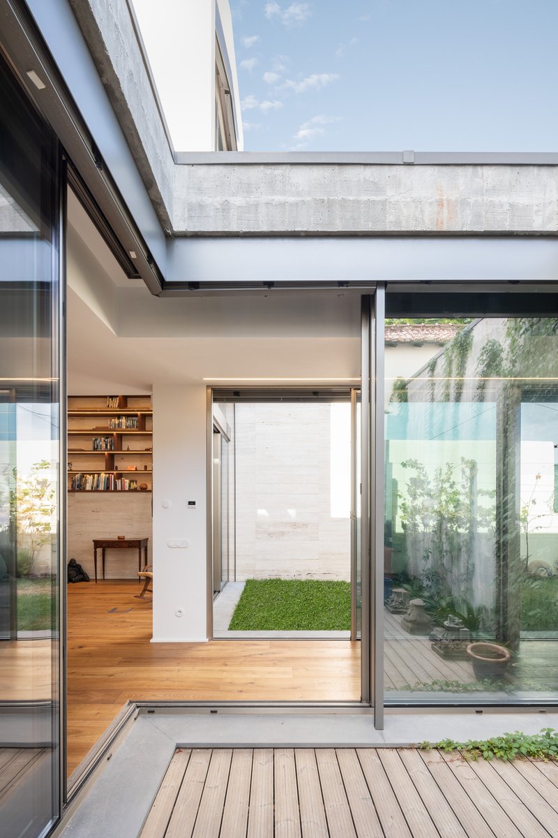 Concrete beam spanning above timber deck and glass doors framing views into interior spaces