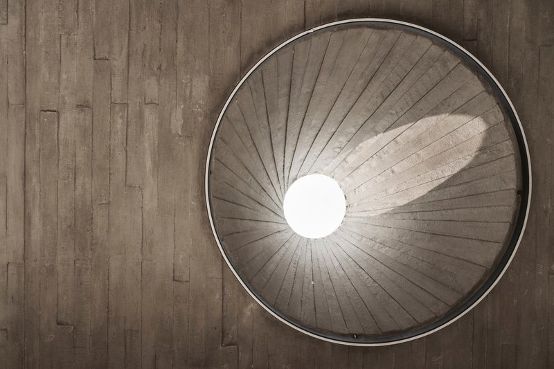 View up into circular skylight with board-formed concrete radiating pattern and central opening