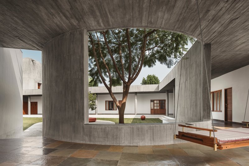 Covered passage with board-formed concrete vault framing a tree in the courtyard beyond
