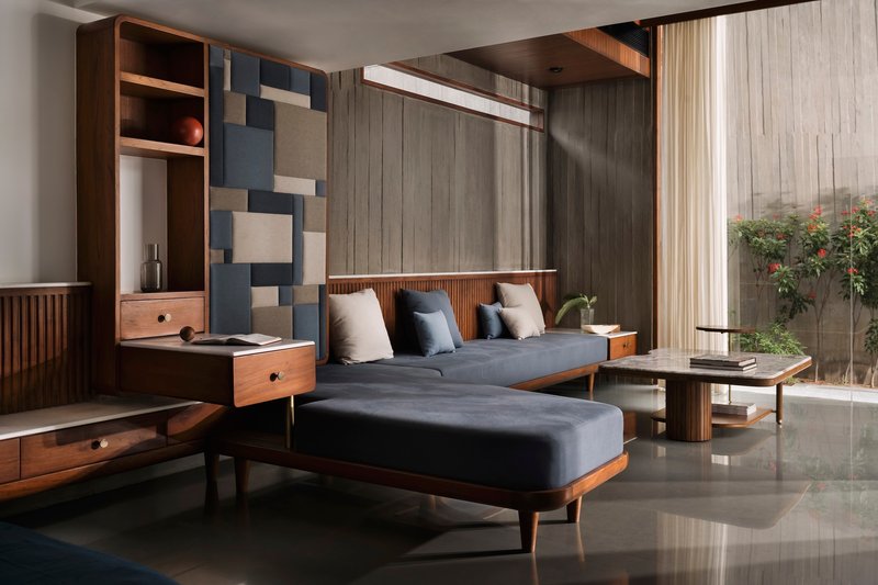 Living room with geometric wall panels, timber storage unit, and glazed doors opening to a planted courtyard