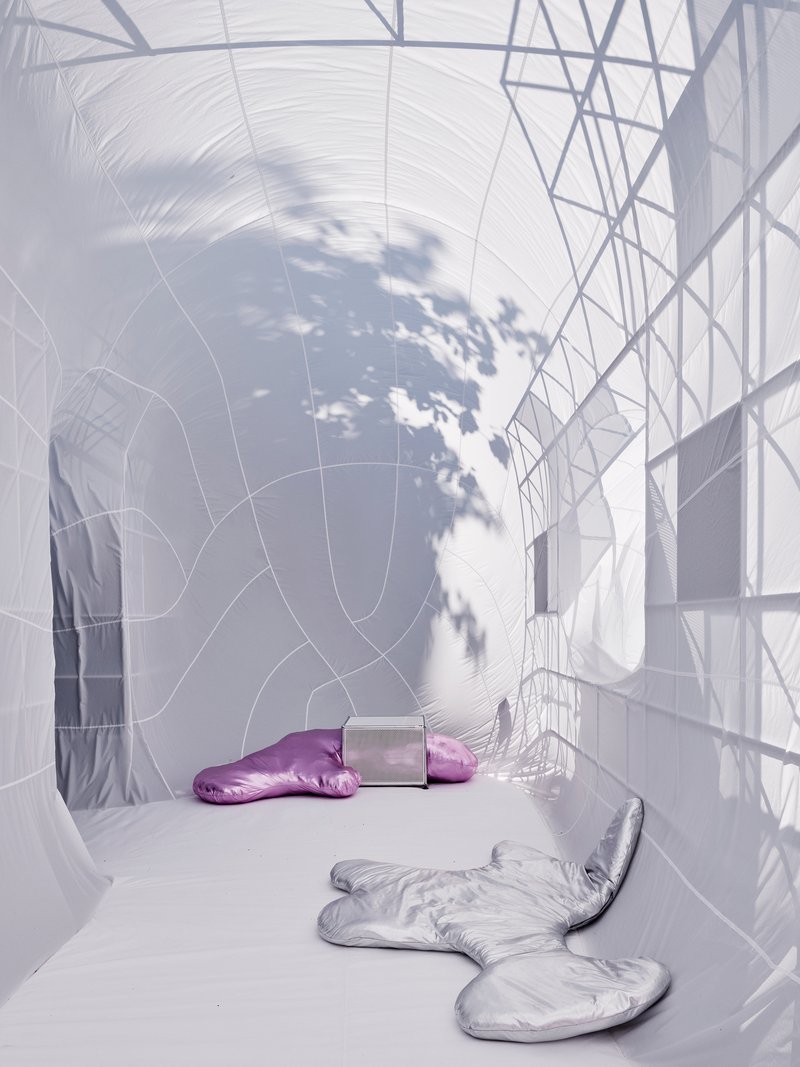 White fabric chamber with tree shadow cast across the membrane surface and two silver cushions on floor