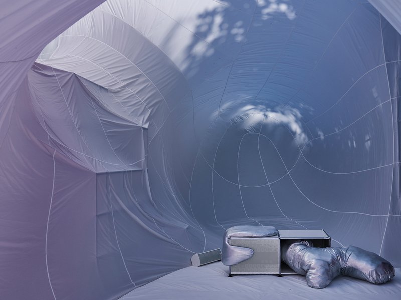 Interior view of the pale inflatable fabric with circular openings and clouds reflected on the surface