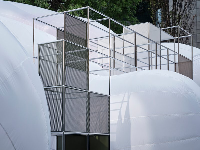 Aluminum frame shelving system with mesh and glass panels rising above inflatable dome structures