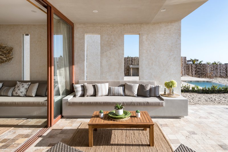 Covered outdoor terrace with built-in concrete seating and timber framed sliding doors opening to the interior