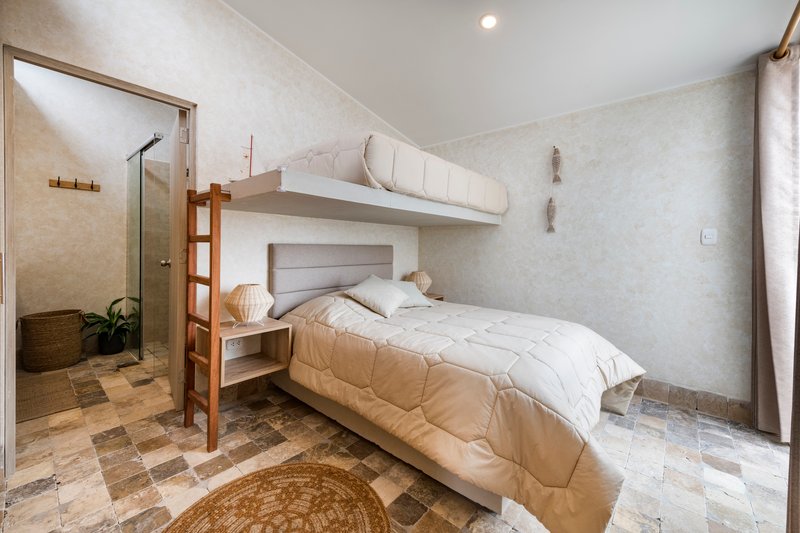 Bedroom with built-in bunk bed and ensuite bathroom visible through open timber-framed door