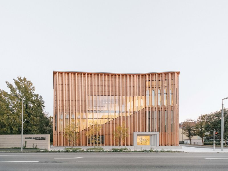Street view of the vertical timber slat facade with glazed openings under overcast light