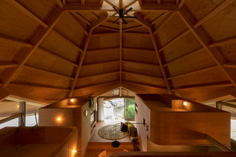 Overhead view into the plywood-lined living space illuminated by warm sconces at dusk