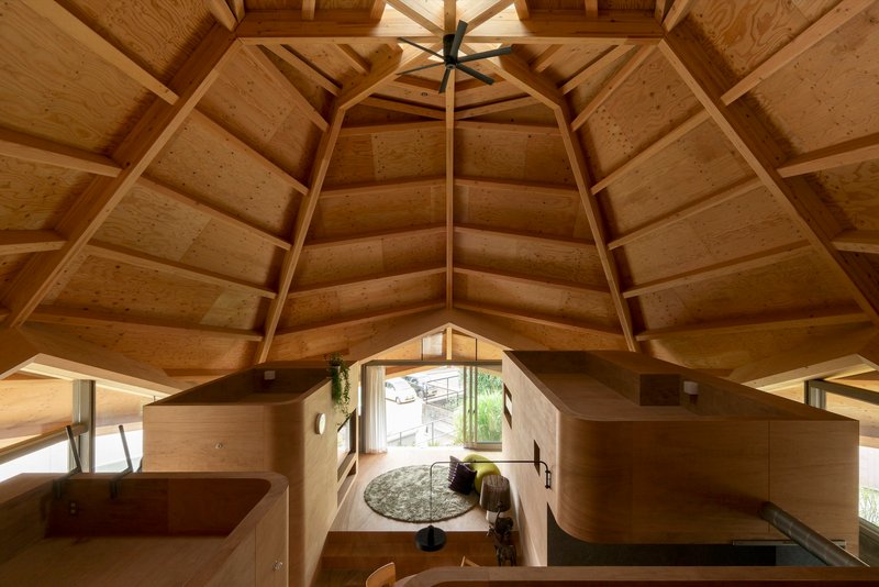 View down into the plywood interior volumes from an upper platform beneath the faceted timber ceiling