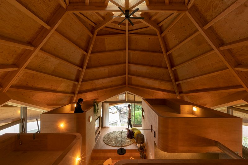 Overhead view from the loft showing the polygonal timber ceiling and plywood partitions enclosing the living space below