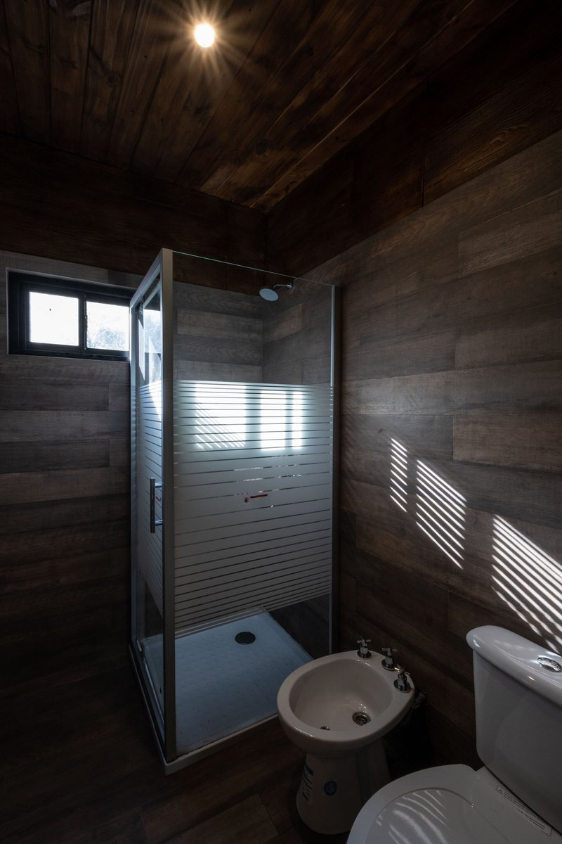 Bathroom with horizontal wood cladding and striped light through a frosted glass shower door