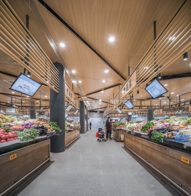 Central aisle with timber ceiling panels, suspended screens and vegetable displays flanking both sides