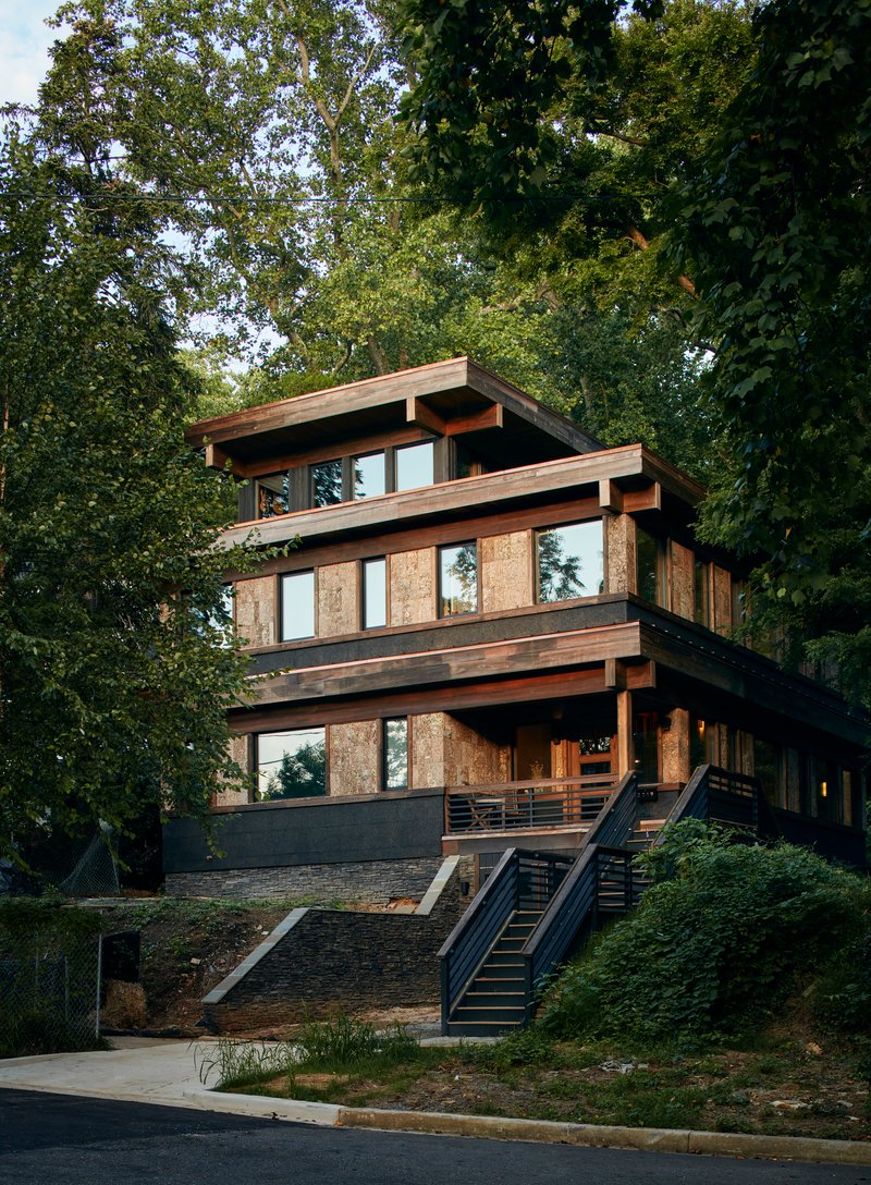 Street-facing facade showing stacked timber-framed volumes with vertical wood panels and a metal exterior staircase