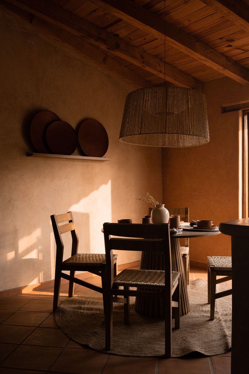 Dining area with woven pendant light and timber ceiling catching warm sunlight through a window