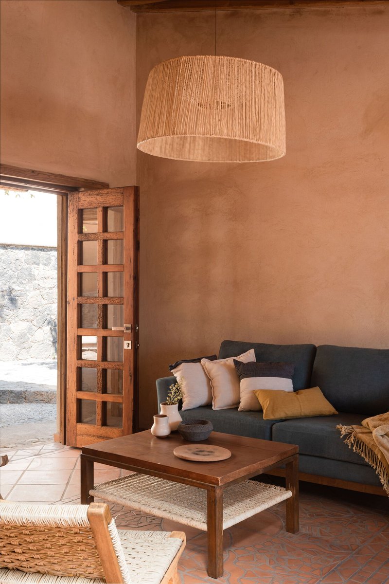 Living room with gridded timber door opening to a courtyard and raked woven pendant overhead