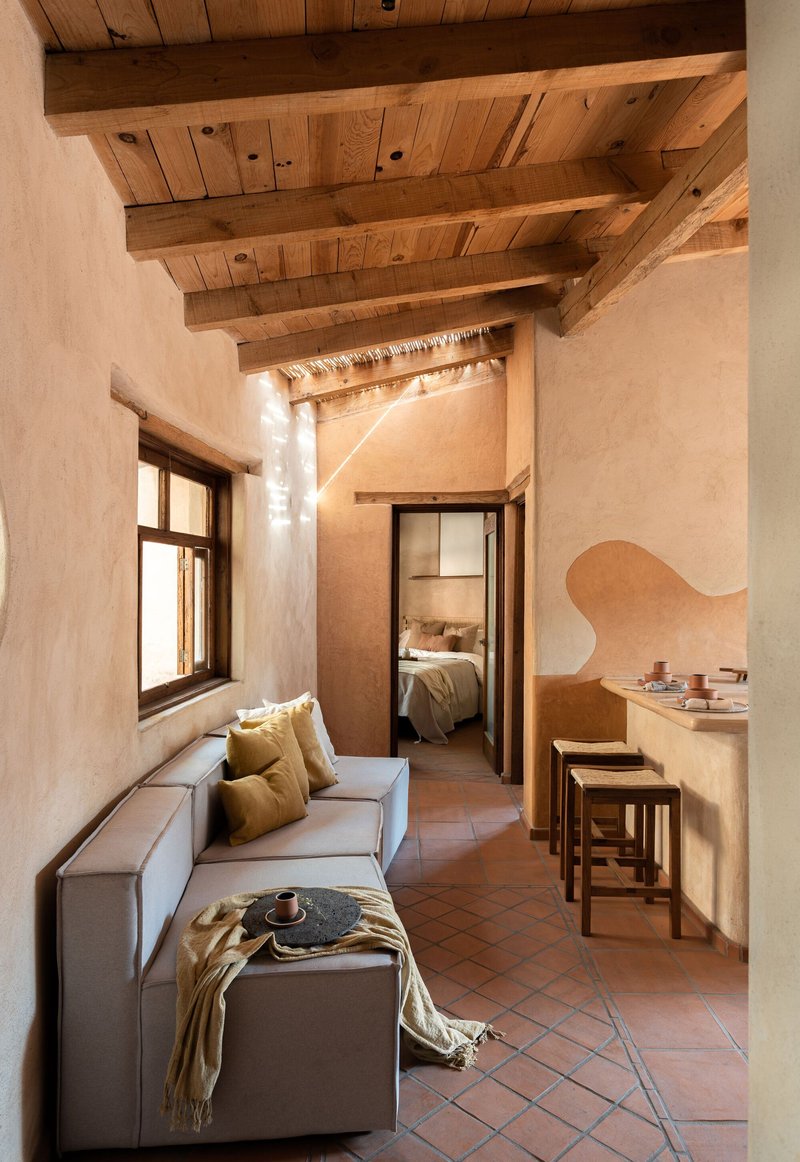 Interior corridor with exposed timber beam ceiling and terracotta floor tiles leading to bedroom