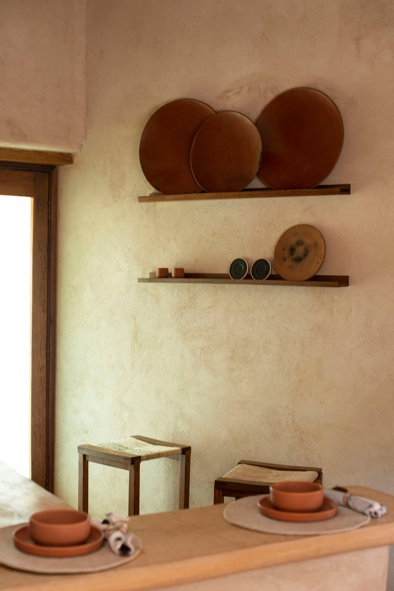 Two floating timber shelves displaying ceramic platters against a textured plaster wall