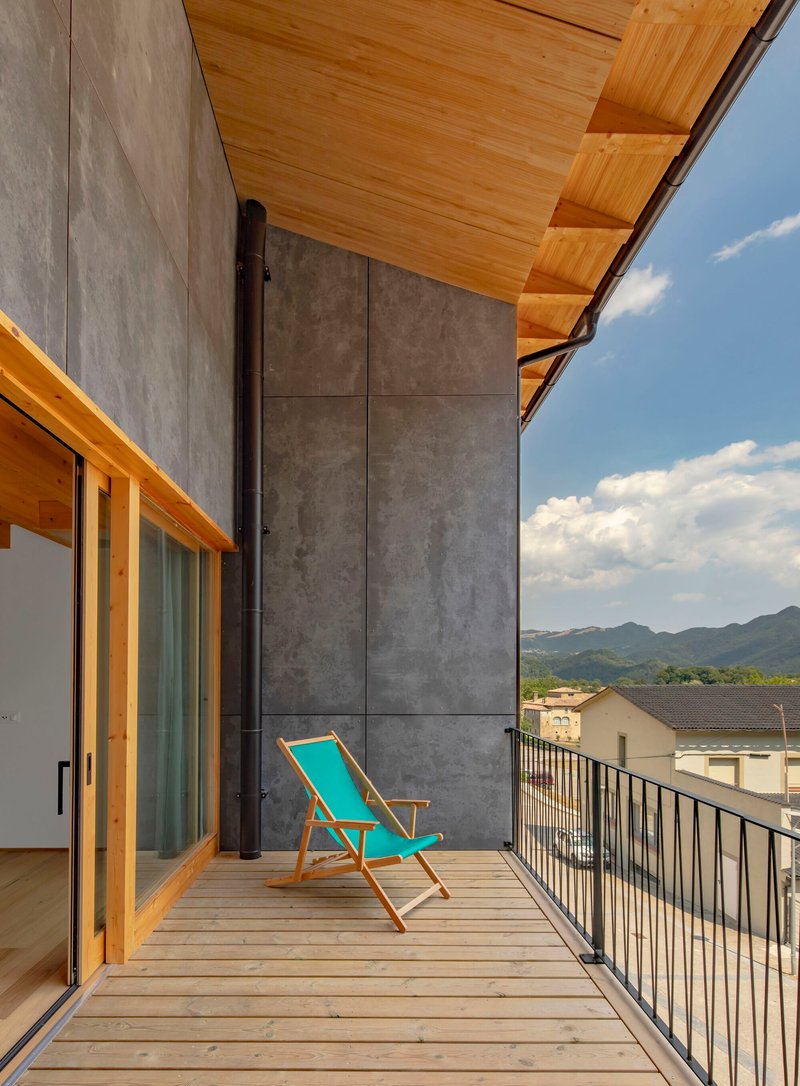 Timber deck balcony with metal railing and turquoise chair looking toward distant mountains