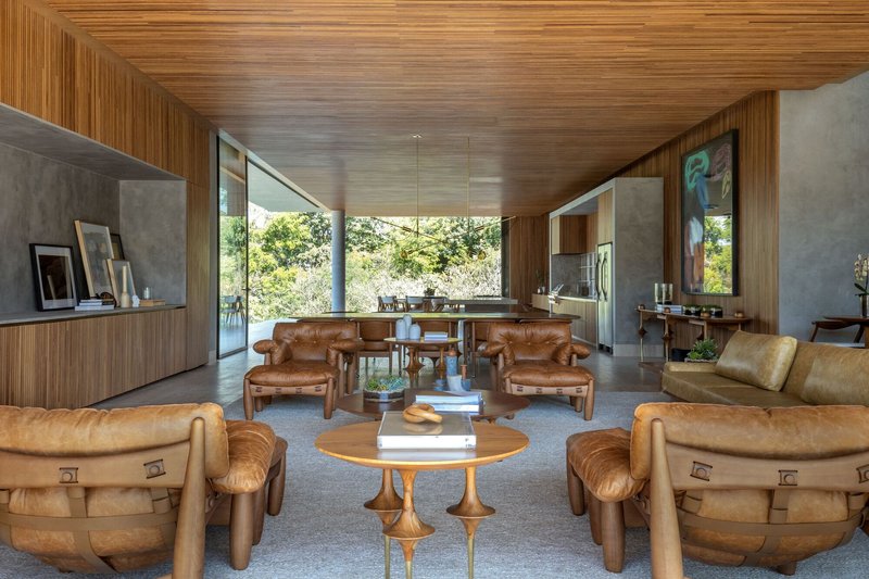 Living area with leather seating beneath horizontal timber ceiling opening to glazed perimeter walls