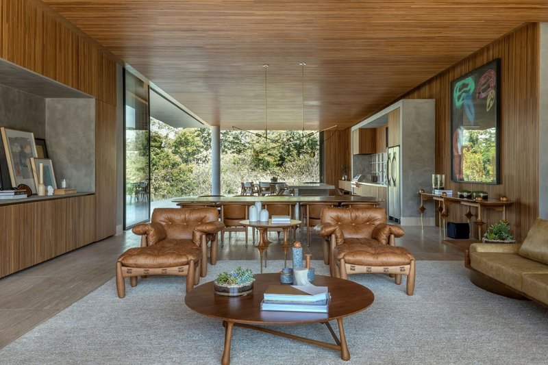 Central living space with timber ceiling canopy and concrete walls framing kitchen and outdoor terraces