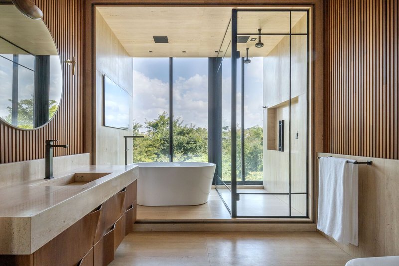 Bathroom with freestanding tub and steel-framed glass shower enclosure overlooking treetops
