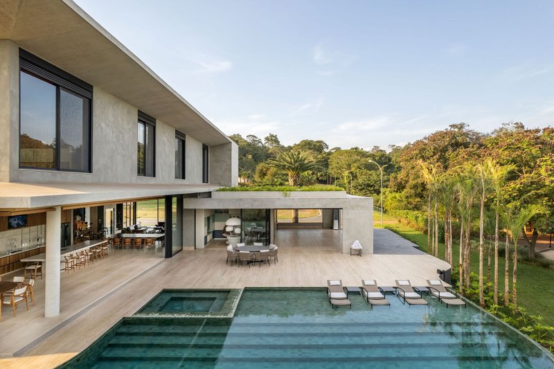 Rear terrace with stepped pool and cantilevered concrete overhangs overlooking dense forest canopy